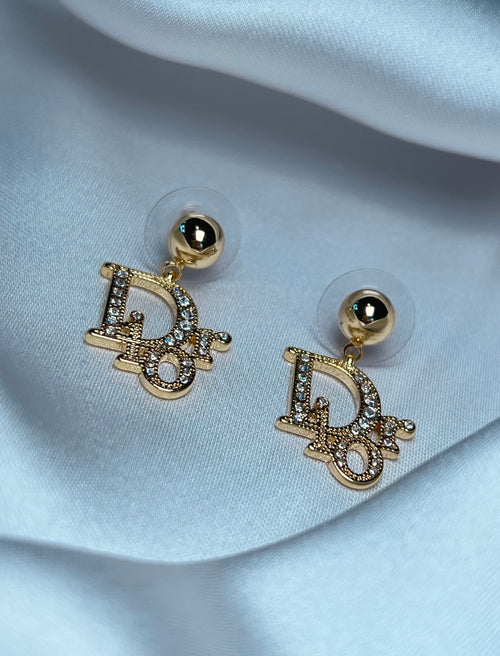 Luxury gold crystal statement earrings photographed on elegant satin backdrop
